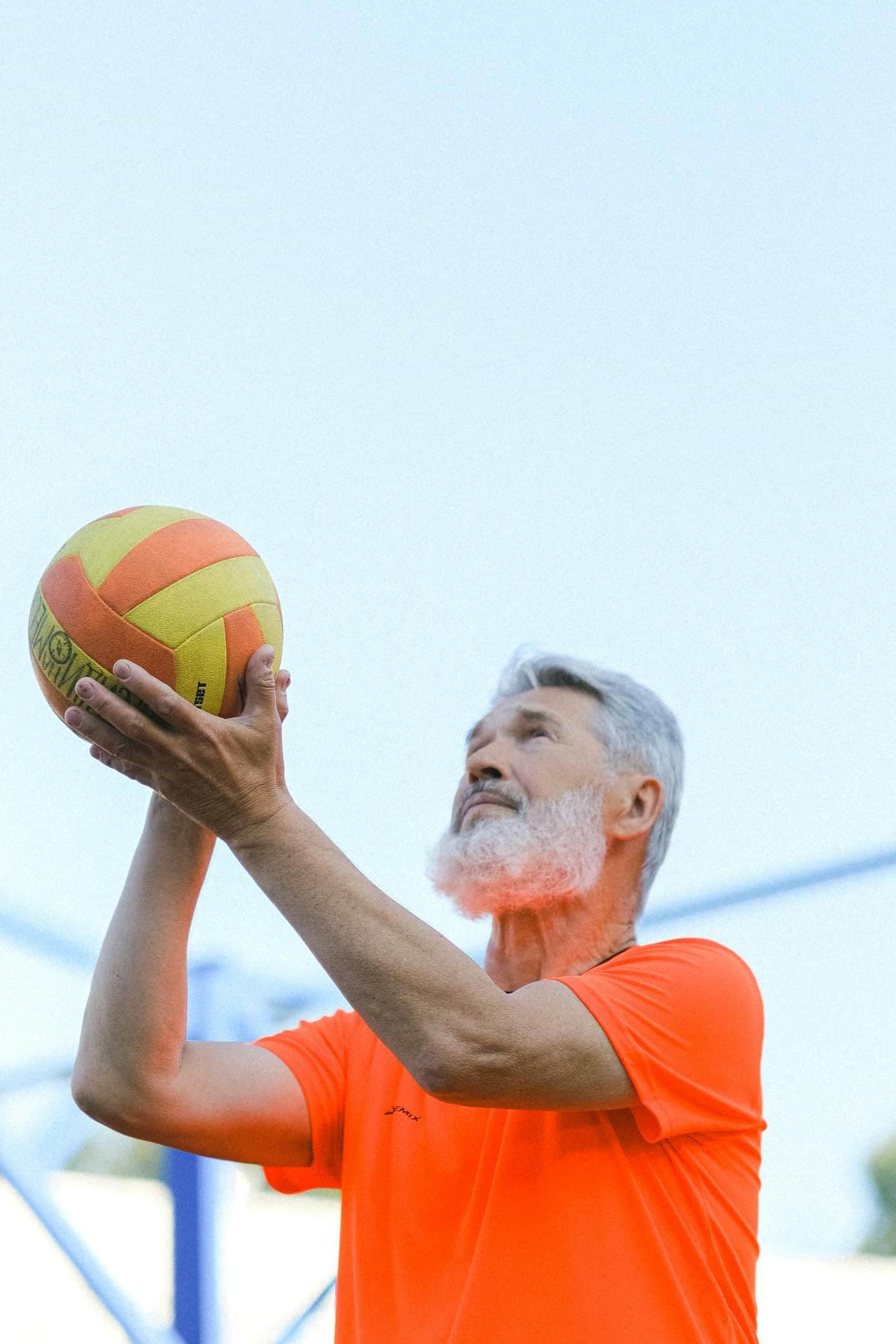 Elderly man playing volleyball on stadium