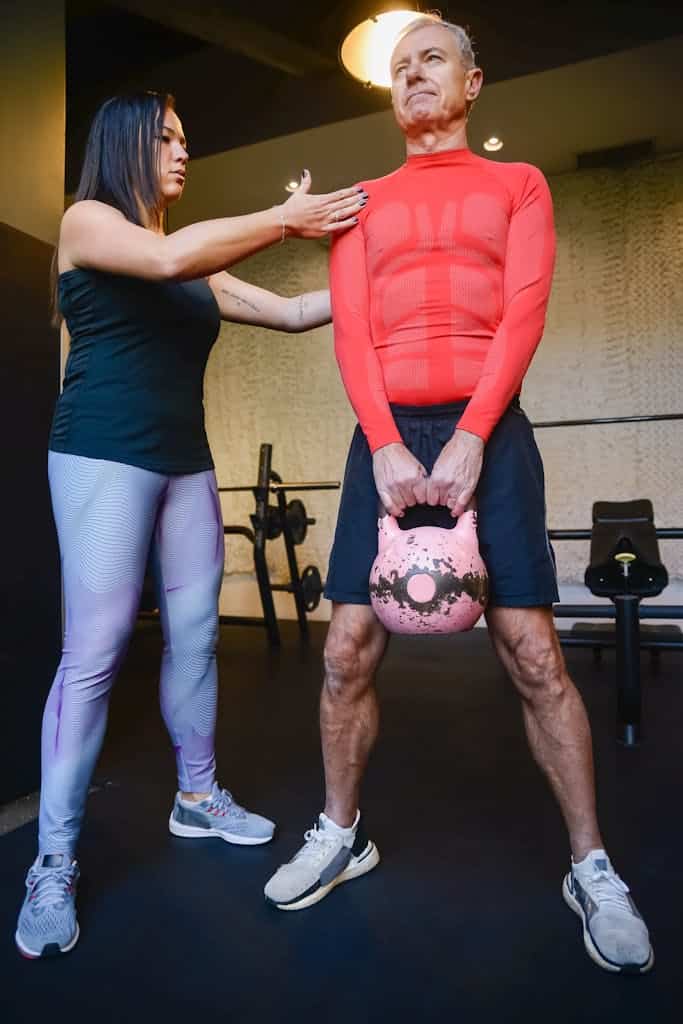 Man in Red Long Sleeve Shirt Holding a Kettle Bell