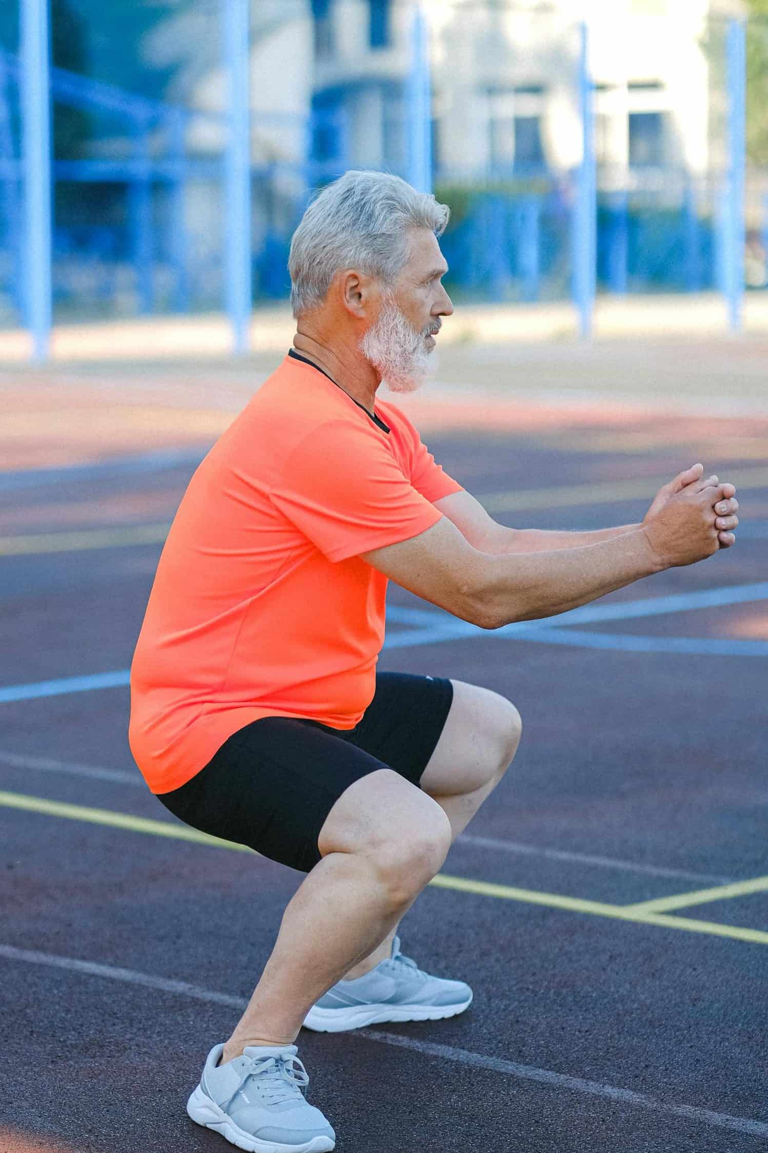 Mature sportsman doing exercises on stadium